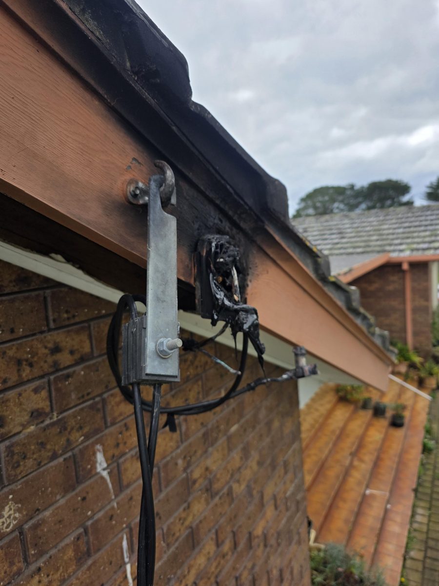 Melted, burnt cable connection at the roof edge of a house